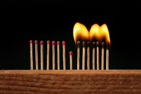 Burning and non-burning matches on dark background. Concept of social distance