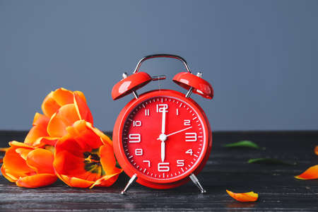 Alarm clock and flowers on table. Spring time