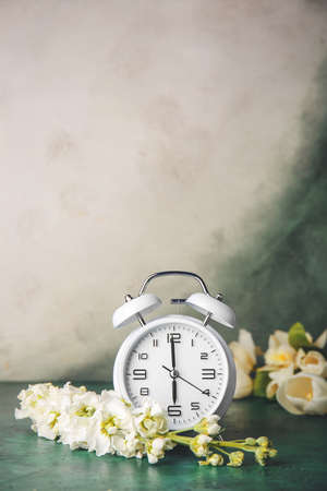Alarm clock and flowers on table. Spring timeの写真素材