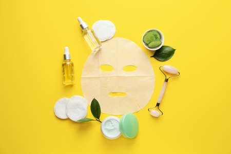 Composition with fabric facial mask, cosmetics and cucumber on color backgroundの写真素材