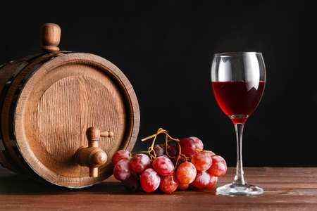 Wooden barrel and glass of wine on dark background