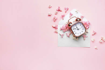 Alarm clock and flowers with envelope on color background. Spring timeの写真素材