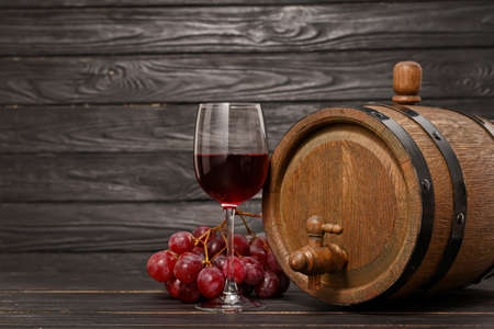 Wooden barrel and glass of wine on dark backgroundの写真素材