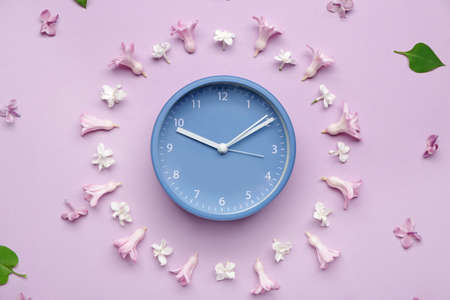 Alarm clock and flowers on color background. Spring timeの写真素材