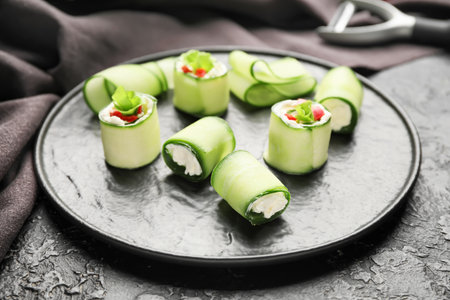 Plate with tasty cucumber rolls on dark backgroundの写真素材