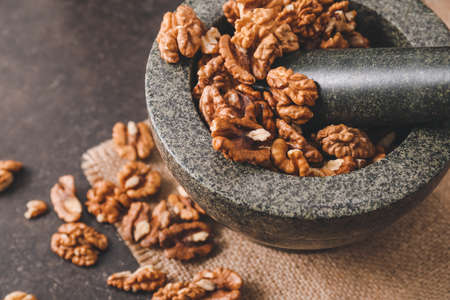 Mortar and pestle with tasty walnuts on tableの写真素材