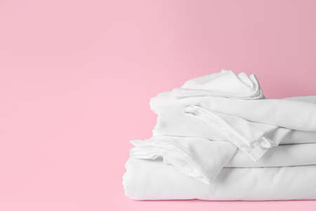 Stack of clean bed sheets on color background