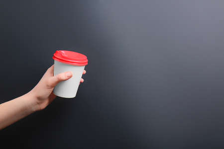 Hand with takeaway cup for drink on dark backgroundの写真素材