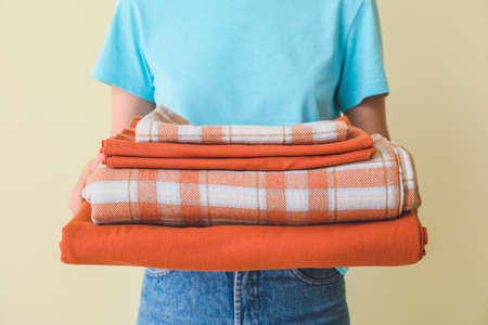 Woman holding stack of clean bed sheets on color backgroundの写真素材