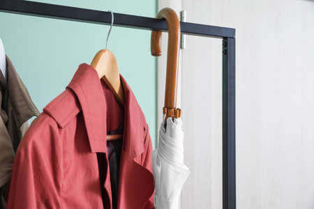 Stylish umbrella with clothes in interior of hallの写真素材