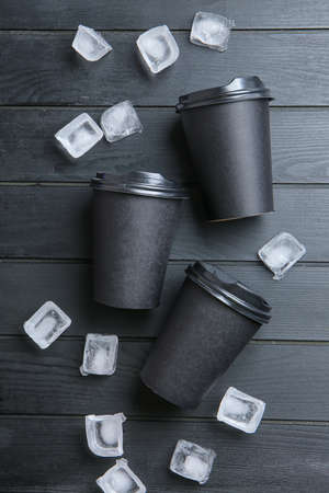 Blank cups and ice cubes on dark wooden backgroundの写真素材