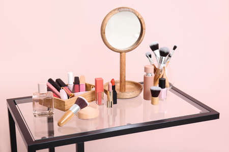 Set of makeup cosmetics with brushes and mirror on tableの写真素材