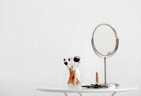 Set of makeup cosmetics with brushes and mirror on tableの写真素材