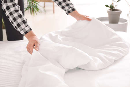 Woman making bed at homeの写真素材