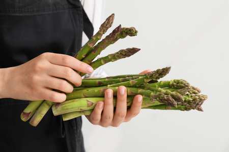 Woman with fresh asparagus on light background, closeupの写真素材