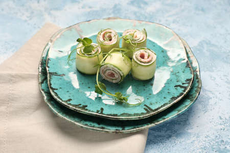Plates with tasty cucumber rolls on color backgroundの写真素材