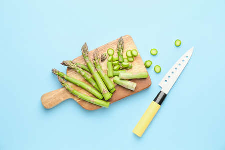 Cutting board with fresh asparagus and knife on color backgroundの写真素材