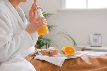 Young woman having breakfast on bed in hotel room