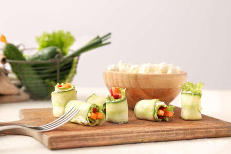 Board with tasty cucumber rolls on tableの写真素材