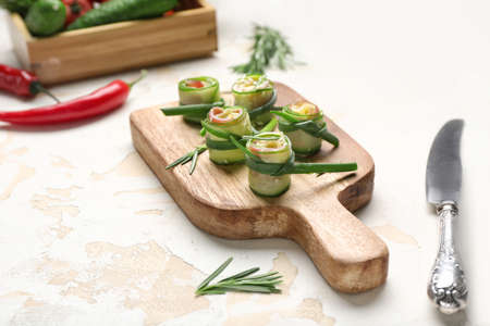 Board with tasty cucumber rolls on light backgroundの写真素材