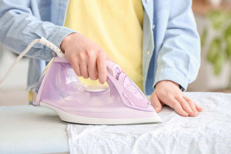 Young woman ironing laundry at home, closeupの写真素材