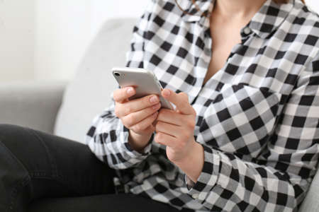 Young woman using mobile phone at homeの写真素材