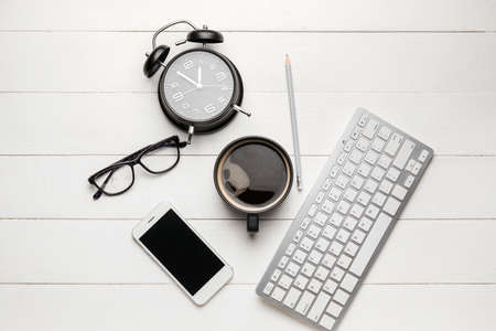 Composition with cup of coffee, computer keyboard and mobile phone on white wooden background