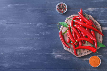 Hot chili pepper with spices on dark wooden background