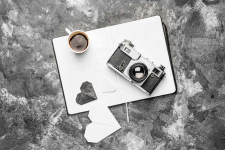 Composition with cup of coffee, photo camera and notebook on gray backgroundの写真素材