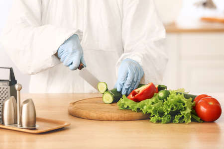 Woman in biohazard suit cooking in kitchenの写真素材