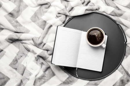 Tray with cup of coffee and book on plaidの写真素材