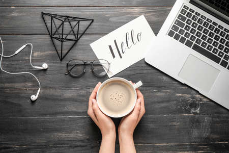 Female hands with cup of coffee on dark wooden backgroundの写真素材