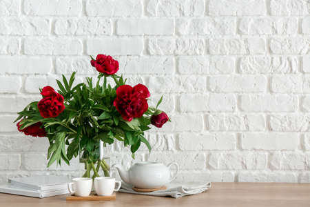 Teapot with cups and bouquet of flowers on kitchen counterの写真素材