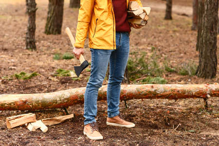Handsome lumberjack with ax in forest