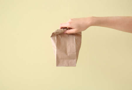 Hand with paper bag on color backgroundの写真素材