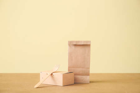 Paper bag, box with food and fork on tableの写真素材