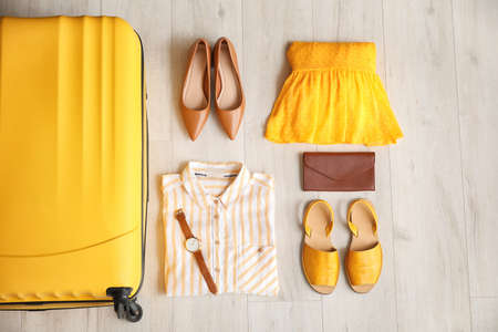 Packed suitcase, clothes and accessories on wooden backgroundの写真素材