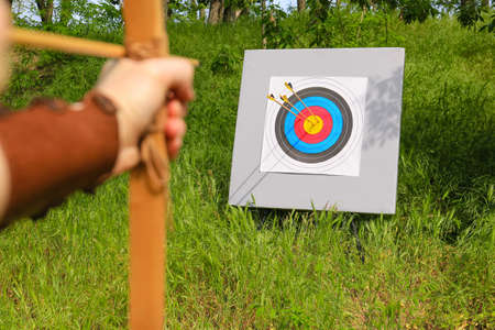 Woman practicing archery in forest, closeup