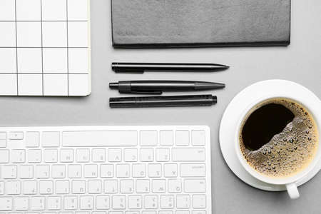 Cup of coffee, stationery and PC keyboard on gray backgroundの写真素材