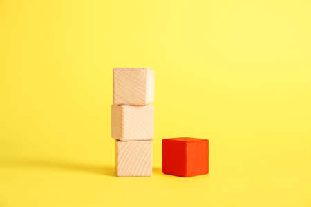 Red cube among wooden ones on color background. Concept of uniquenessの写真素材