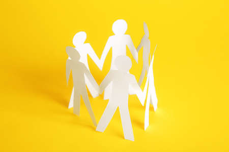 Paper human figures holding hands on color background. Unity concept