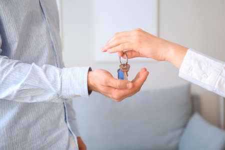 Real estate agent giving young man key from his new flat