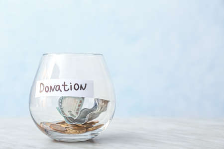 Glass bowl with money on light background. Donation conceptの写真素材