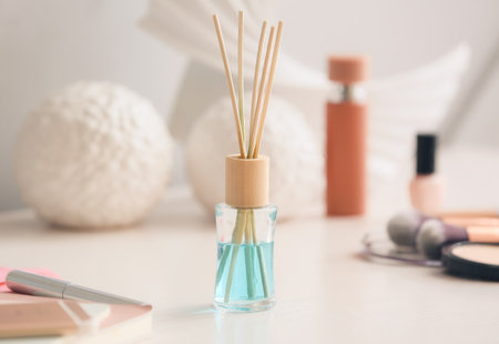 Reed diffuser and cosmetics on table in room