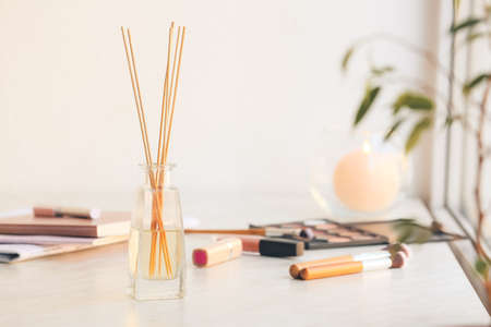 Reed diffuser and cosmetics on table in roomの写真素材