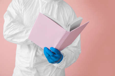 Man in biohazard suit reading book on color background, closeupの写真素材