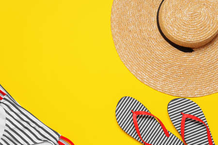 Straw hat with beach clothes on color background