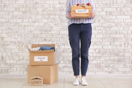 Woman with donations near brick wallの写真素材