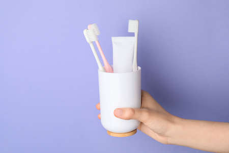 Female hand with toothbrushes and paste on color backgroundの写真素材