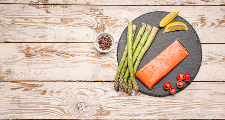 Asparagus with salmon, lemon, chili pepper and spices on tableの写真素材
